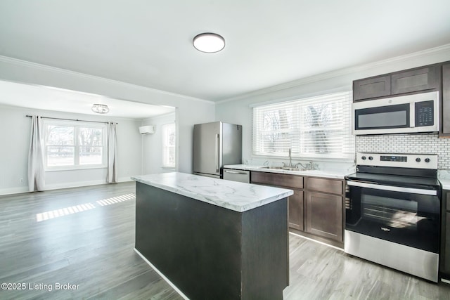 kitchen featuring sink, an AC wall unit, light hardwood / wood-style floors, a kitchen island, and appliances with stainless steel finishes