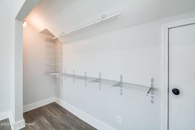 walk in closet with vaulted ceiling and dark hardwood / wood-style floors