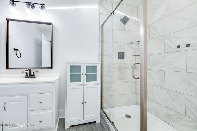 bathroom featuring hardwood / wood-style floors, a shower with door, and vanity