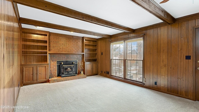 unfurnished living room featuring carpet flooring, beam ceiling, built in features, and wood walls