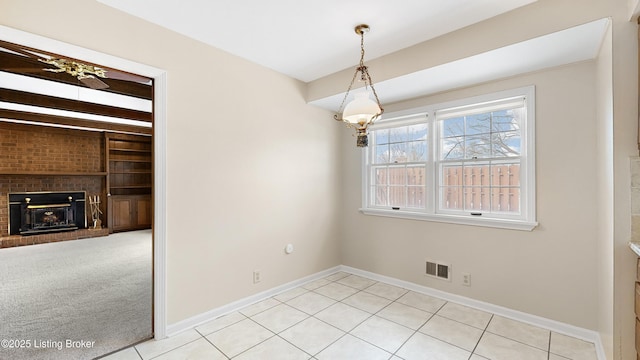 unfurnished dining area featuring light carpet, a brick fireplace, and built in shelves