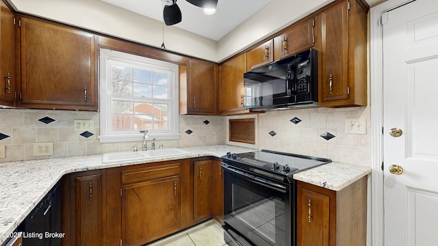 kitchen with sink, decorative backsplash, light tile patterned floors, light stone counters, and black appliances