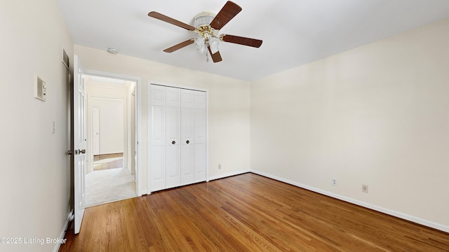 unfurnished bedroom featuring hardwood / wood-style flooring, ceiling fan, and a closet