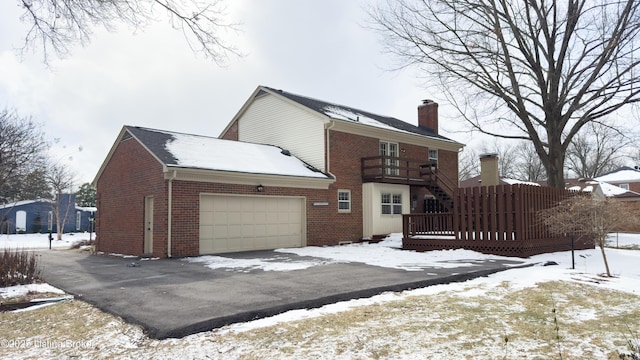 snow covered property with a garage and a balcony