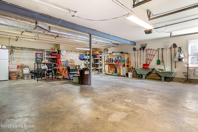 garage with a workshop area, a garage door opener, and white fridge