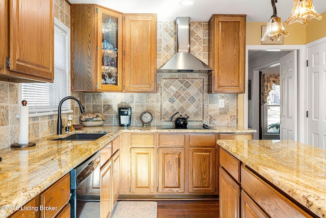 kitchen with wall chimney range hood, sink, dishwasher, hanging light fixtures, and light stone counters