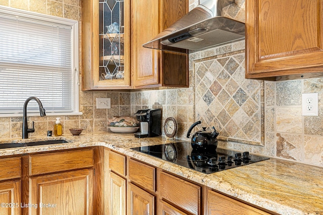 kitchen with sink, backsplash, light stone counters, black electric stovetop, and wall chimney exhaust hood