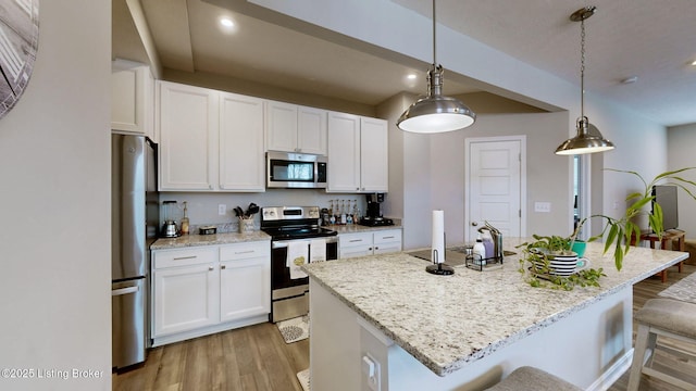 kitchen featuring a kitchen island with sink, white cabinets, and appliances with stainless steel finishes