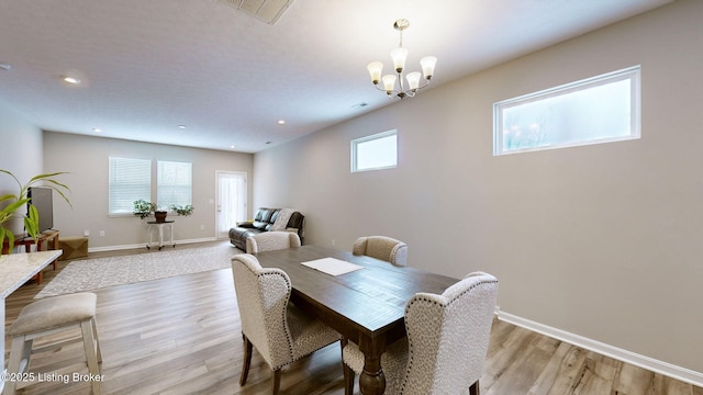 dining room with light hardwood / wood-style floors and a notable chandelier