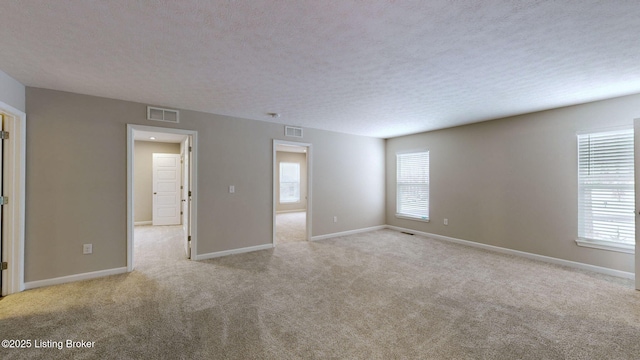 unfurnished room with light colored carpet and a textured ceiling