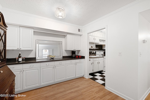 kitchen with white cabinets, a textured ceiling, and electric range