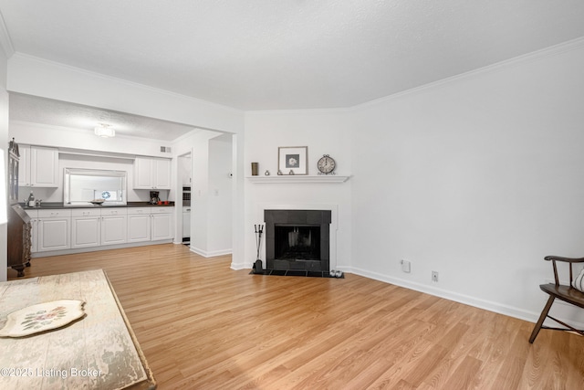 living room featuring a fireplace, a textured ceiling, ornamental molding, and light hardwood / wood-style flooring