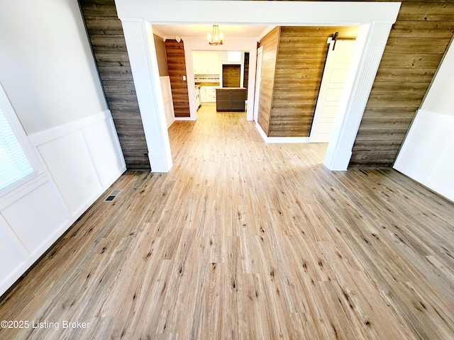 interior space featuring a barn door, light hardwood / wood-style flooring, and a notable chandelier