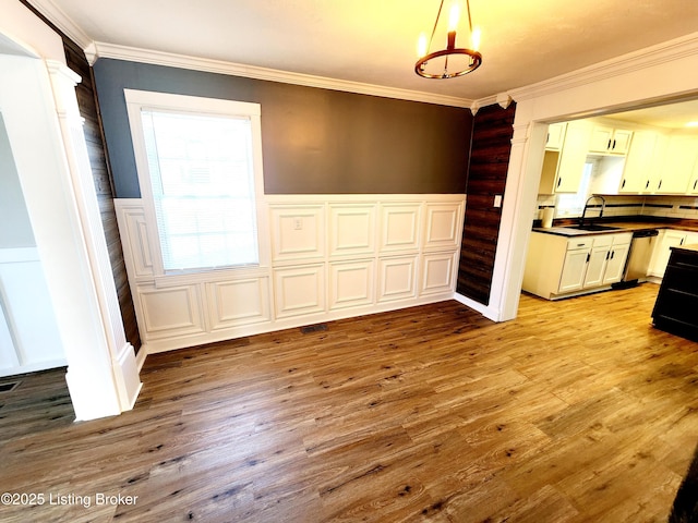 unfurnished dining area with sink, crown molding, and light hardwood / wood-style floors