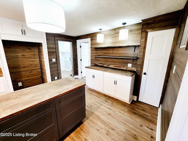 kitchen featuring white cabinetry, wooden counters, a textured ceiling, light wood-type flooring, and pendant lighting