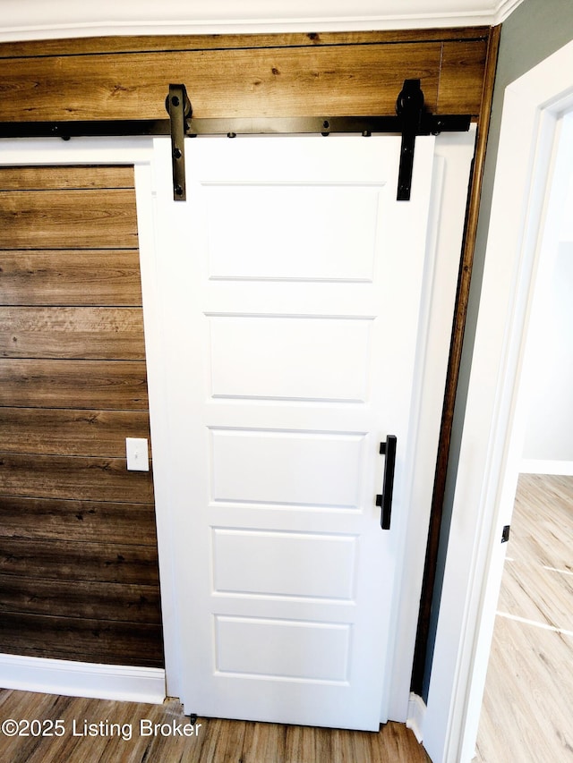 room details featuring wooden walls, a barn door, and hardwood / wood-style floors