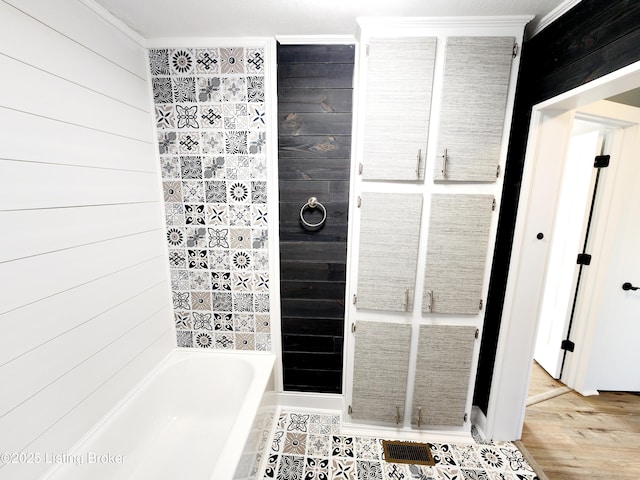 bathroom featuring a tub to relax in, hardwood / wood-style flooring, and wooden walls