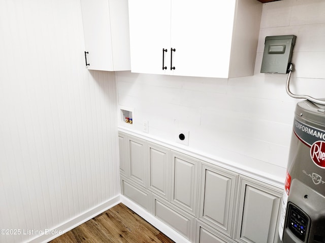 clothes washing area with water heater, washer hookup, dark wood-type flooring, and cabinets