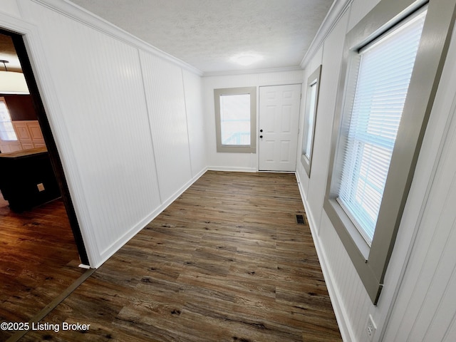 doorway to outside featuring crown molding, dark wood-type flooring, and a textured ceiling