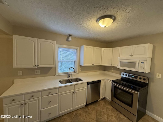 kitchen featuring appliances with stainless steel finishes, a textured ceiling, white cabinetry, and sink