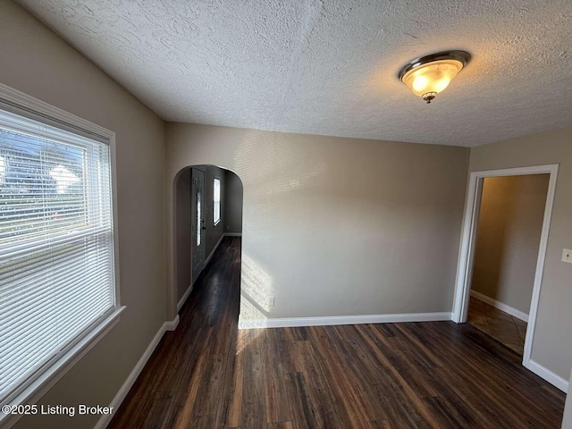 corridor with a textured ceiling and dark hardwood / wood-style floors