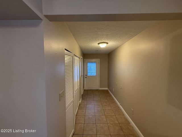 hall featuring light tile patterned floors and a textured ceiling