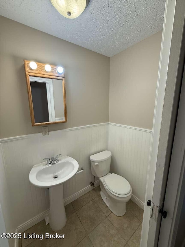 bathroom featuring tile patterned flooring, toilet, and a textured ceiling