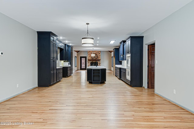 kitchen featuring a center island, double wall oven, decorative light fixtures, and light hardwood / wood-style flooring