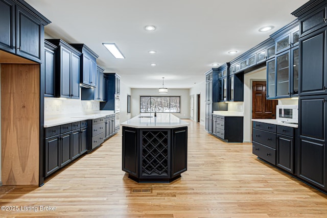 kitchen featuring a center island with sink, backsplash, sink, and light hardwood / wood-style flooring