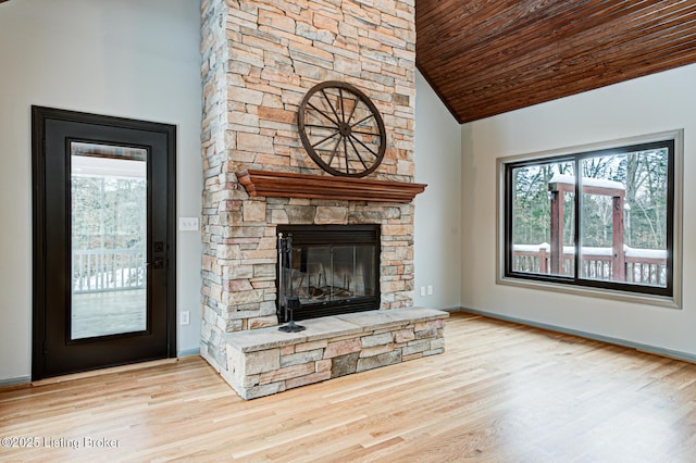 unfurnished living room with light wood-type flooring, a stone fireplace, vaulted ceiling, and wood ceiling