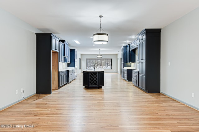 kitchen featuring a center island with sink, pendant lighting, light wood-type flooring, and sink