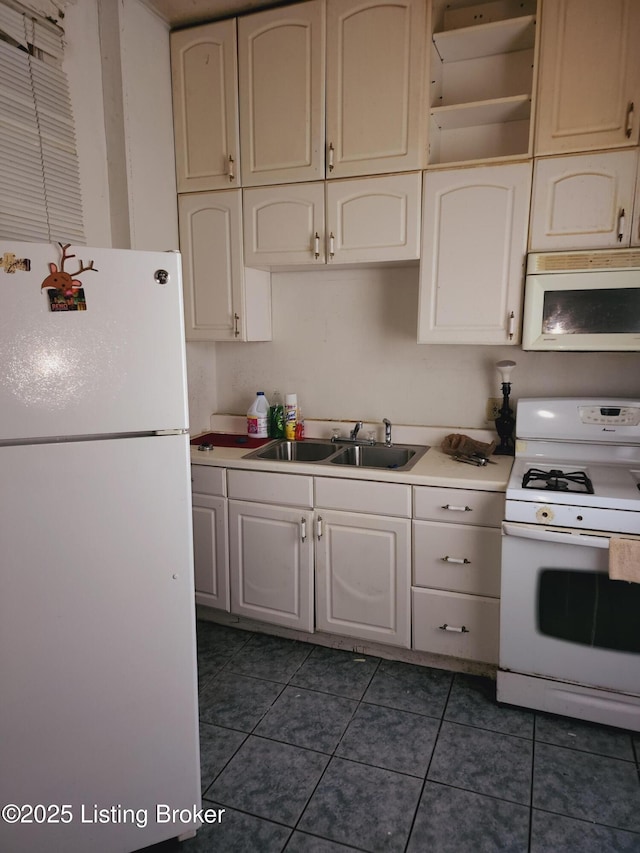 kitchen with sink, dark tile patterned flooring, and white appliances