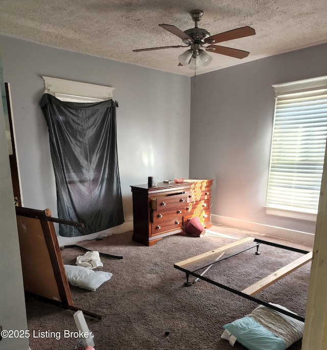 bedroom with ceiling fan, carpet floors, and a textured ceiling