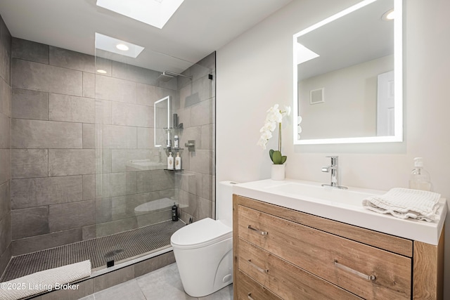 bathroom featuring toilet, tiled shower, a skylight, tile patterned floors, and vanity