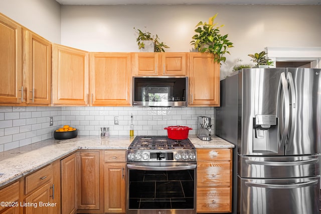 kitchen with stainless steel appliances, backsplash, and light stone countertops