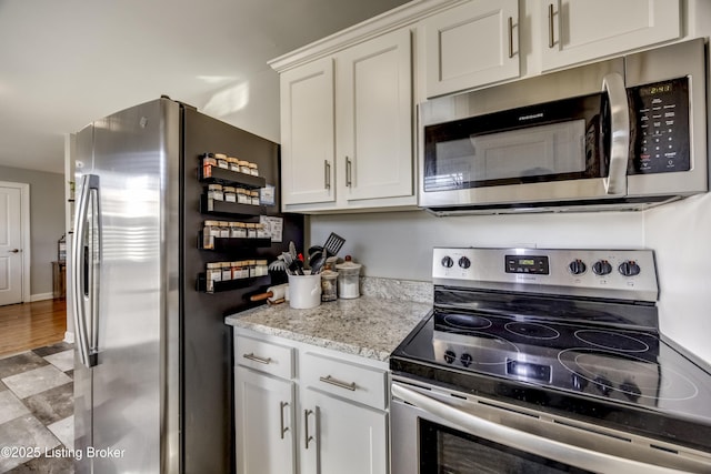 kitchen featuring light stone countertops, appliances with stainless steel finishes, and white cabinetry