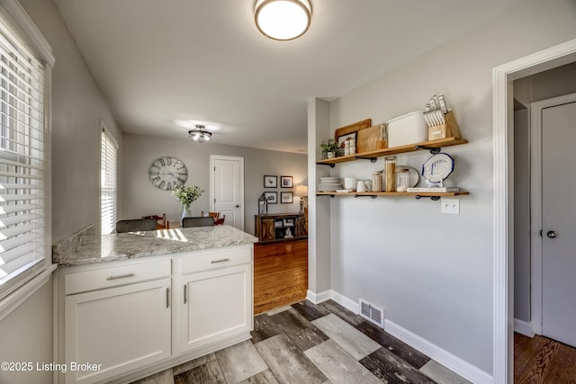 kitchen featuring white cabinetry, light hardwood / wood-style floors, and light stone counters