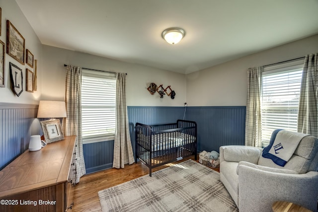 bedroom with light hardwood / wood-style flooring and a nursery area