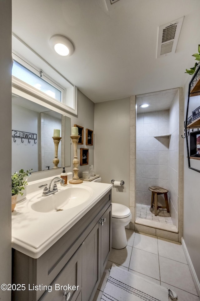 bathroom featuring toilet, tile patterned floors, tiled shower, and vanity