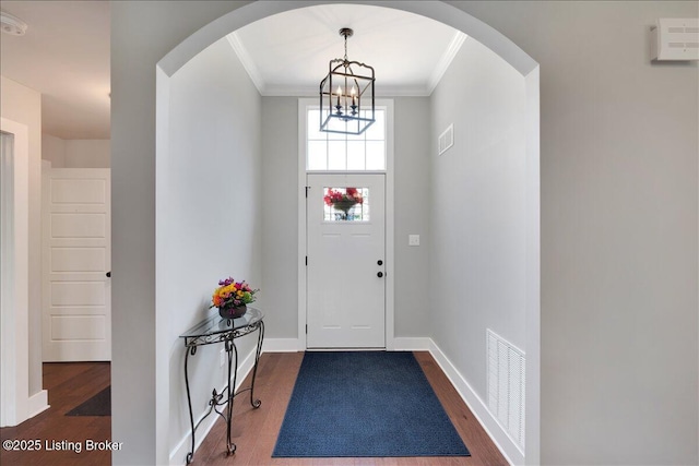 entrance foyer featuring ornamental molding, a chandelier, and dark hardwood / wood-style floors