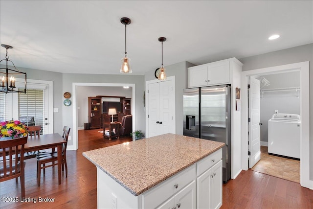 kitchen with washer / clothes dryer, stainless steel fridge, a kitchen island, white cabinets, and decorative light fixtures