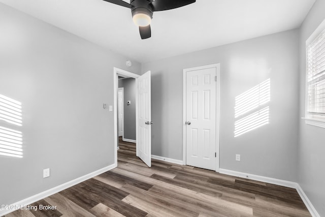 unfurnished bedroom featuring ceiling fan, multiple windows, and dark hardwood / wood-style flooring