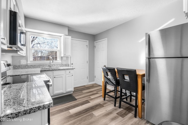 kitchen featuring light stone counters, sink, white cabinets, and stainless steel appliances