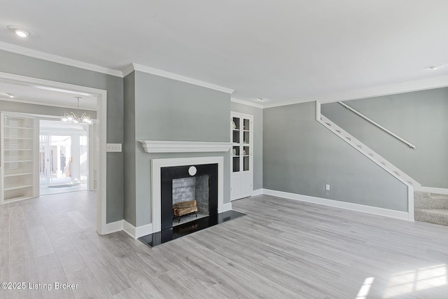 unfurnished living room featuring a notable chandelier, crown molding, built in features, and light wood-type flooring