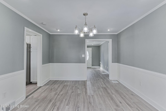 unfurnished dining area with ornamental molding, a chandelier, and light wood-type flooring