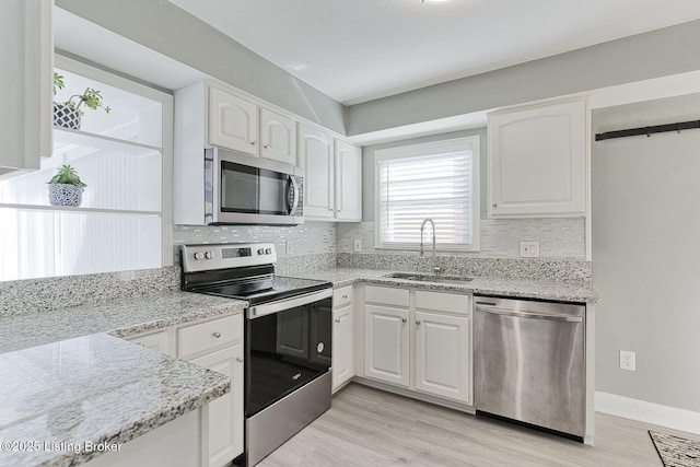 kitchen featuring light stone counters, appliances with stainless steel finishes, sink, and white cabinets