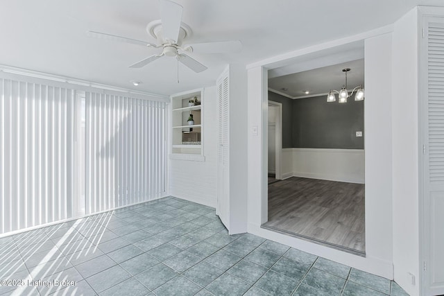 spare room featuring crown molding, tile patterned floors, and ceiling fan with notable chandelier