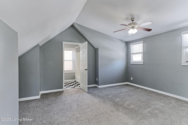 bonus room featuring dark colored carpet, plenty of natural light, lofted ceiling, and ceiling fan