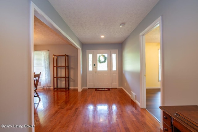 foyer entrance with hardwood / wood-style flooring, a textured ceiling, and a wealth of natural light