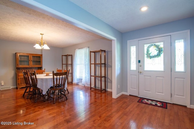 foyer entrance featuring hardwood / wood-style flooring, an inviting chandelier, a textured ceiling, and plenty of natural light